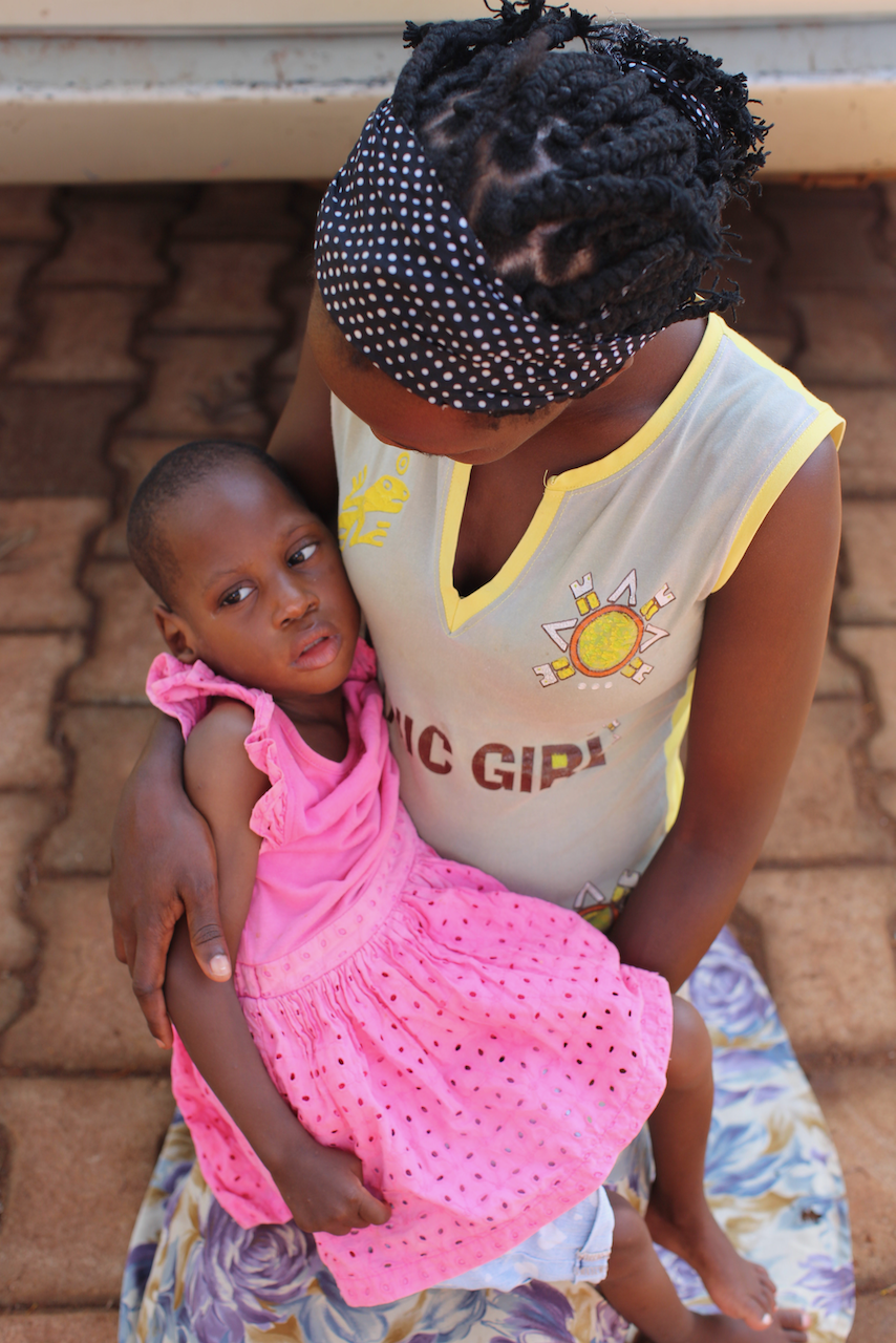 A woman sitting on the ground holding a young girl